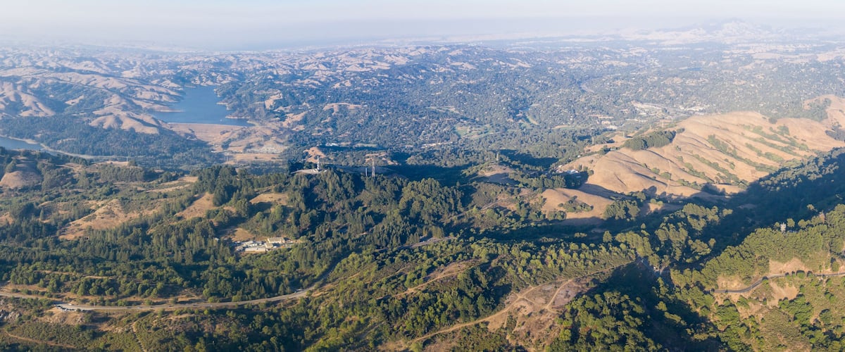 A mountainous landscape with a river, dense forests, and a small settlement.