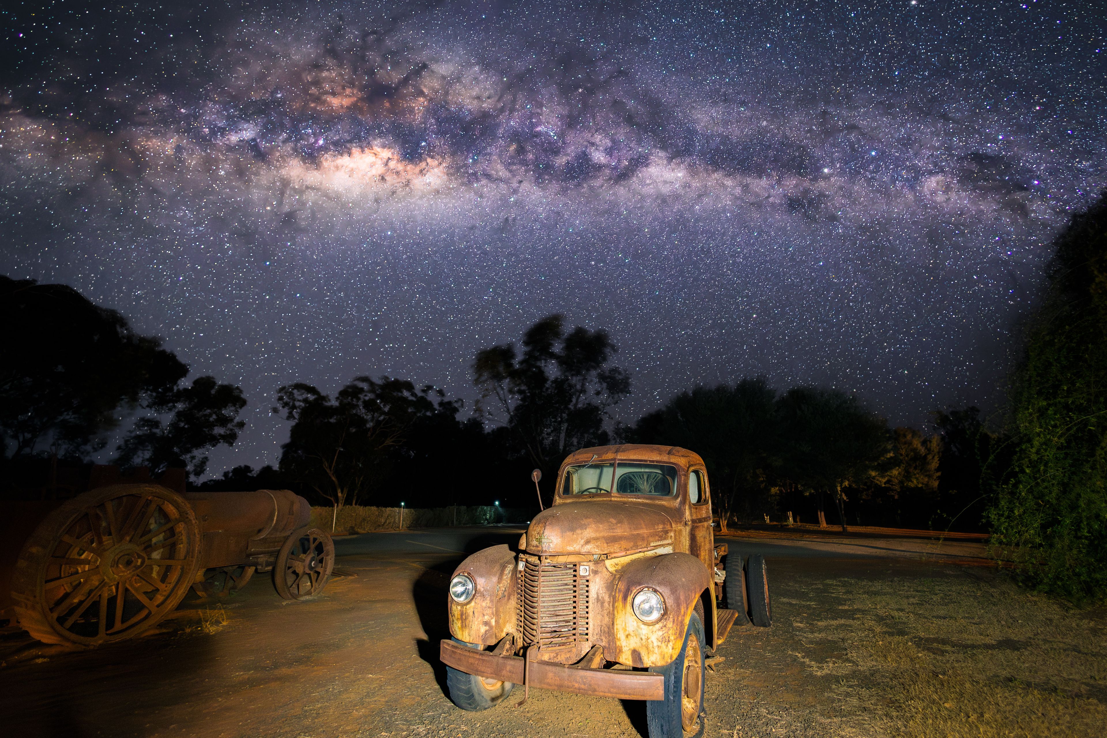 Un'auto d'epoca parcheggiata sotto un cielo stellato con la Via Lattea visibile.