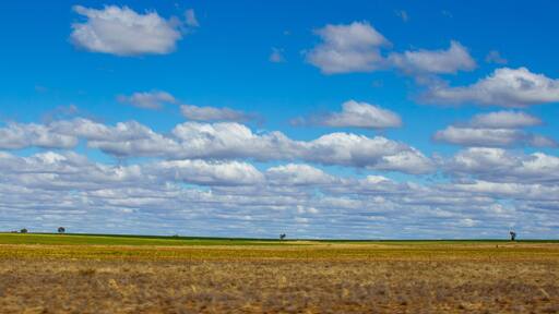 Farmland between Roma and Charleville with cloud formations. Blue sky with trees on hill top. Queensland, Australia.