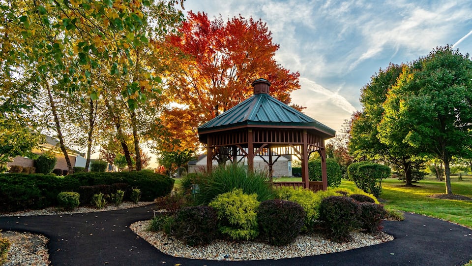 A gazebo surrounded by a landscaped garden with trees displaying autumn foliage.