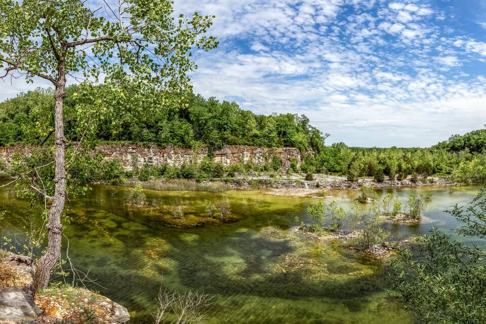 Um rio de águas cristalinas, rodeado por uma floresta densa e penhascos rochosos.