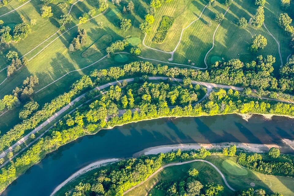 An aerial view of a golf course with multiple fairways, sand bunkers, and water hazards.