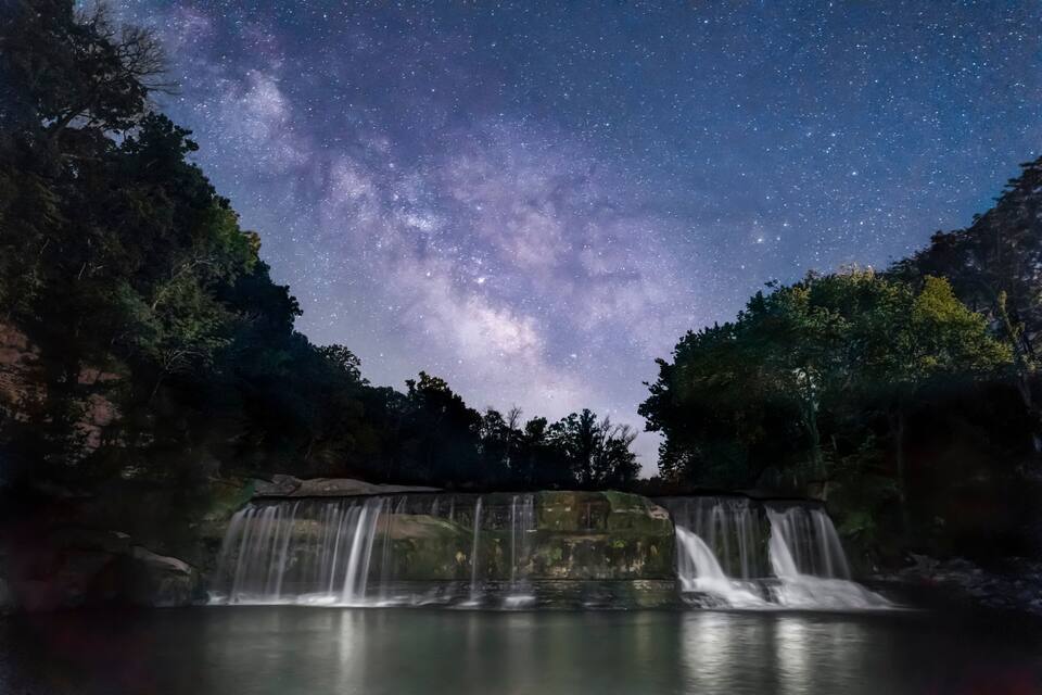 Une cascade avec un ciel étoilé au-dessus.