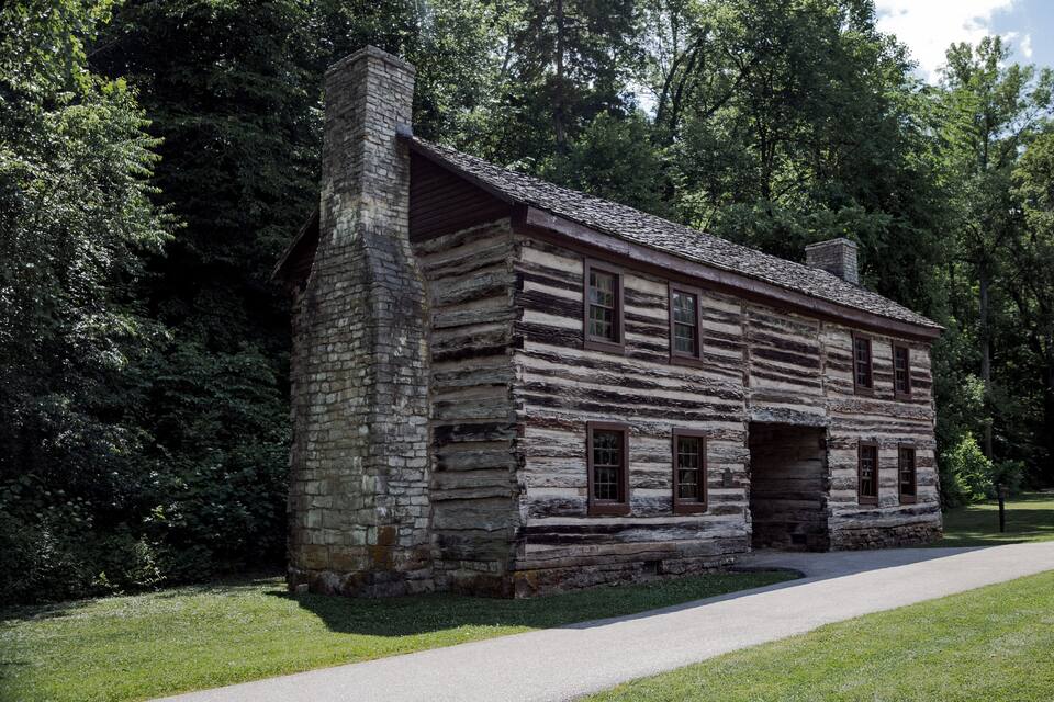Ein rustikales Blockhaus, umgeben von üppigem Grün.