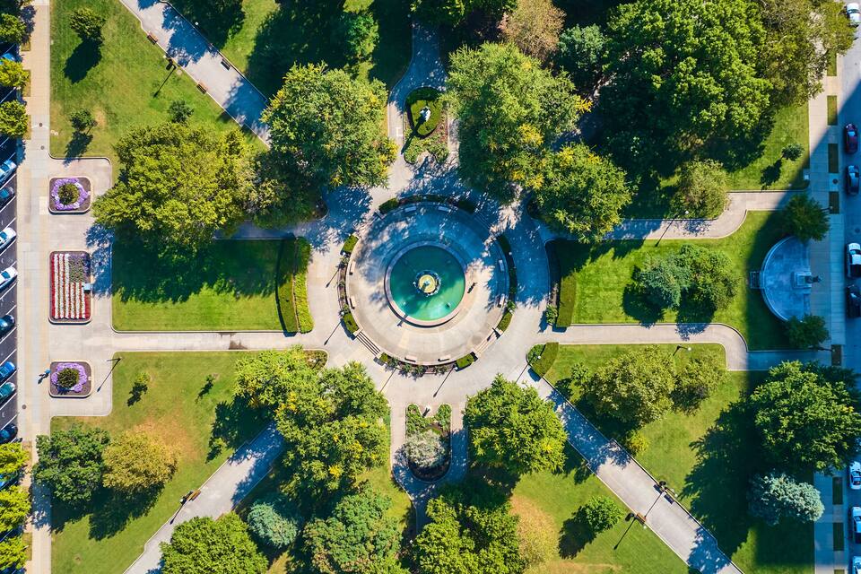 Vista aérea de una glorieta con una fuente central rodeada de vegetación y árboles.