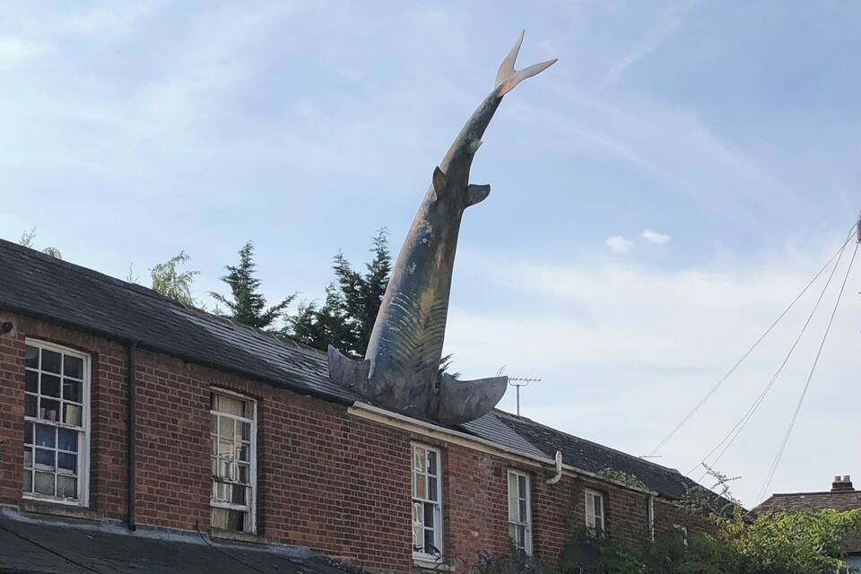 A large whale sculpture on a building roof.