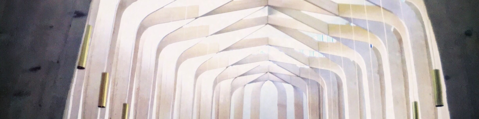 A modern church interior with a unique geometric ceiling design and rows of pews.