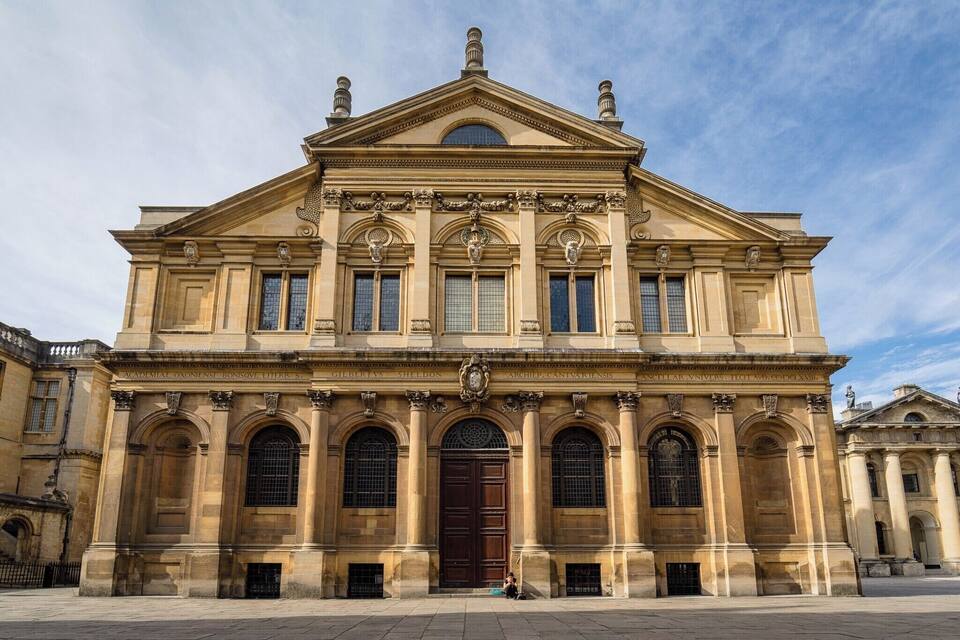 A grand classical building with a large central door, arched windows, and decorative columns.