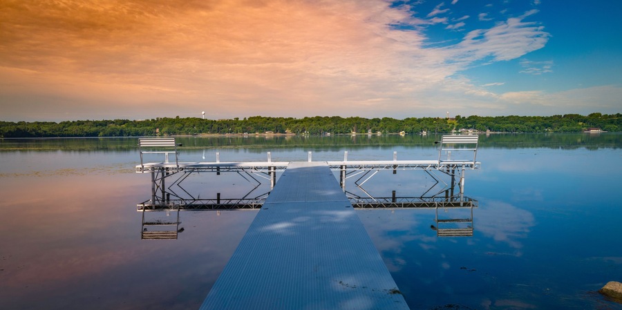 Metal pier boardwalk with benches in the water. Relaxing tranquil natural settings and landscape of Big Stone Lake at the border of Minnesota and South Dakota, USA.