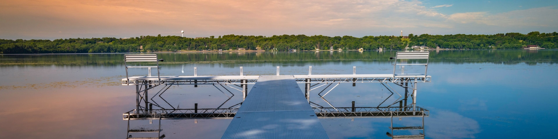 Metal pier boardwalk with benches in the water. Relaxing tranquil natural settings and landscape of Big Stone Lake at the border of Minnesota and South Dakota, USA.
