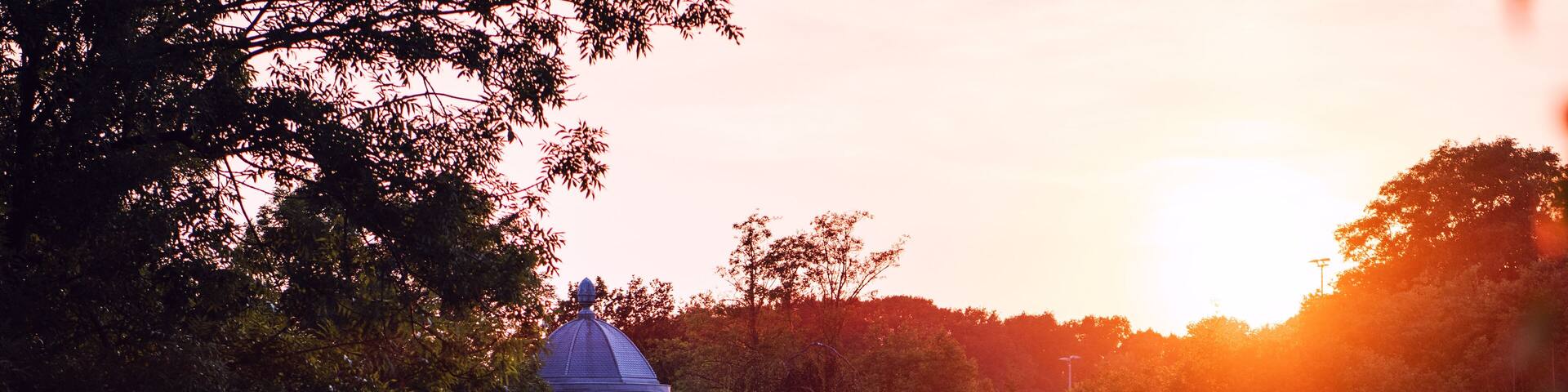 Un pabellón junto a un estanque al atardecer.