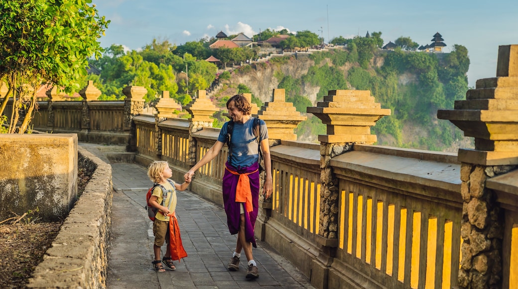 Dad and son travelers in Pura Luhur Uluwatu temple, Bali, Indonesia. Amazing landscape - cliff with blue sky and sea. Traveling with kids concept