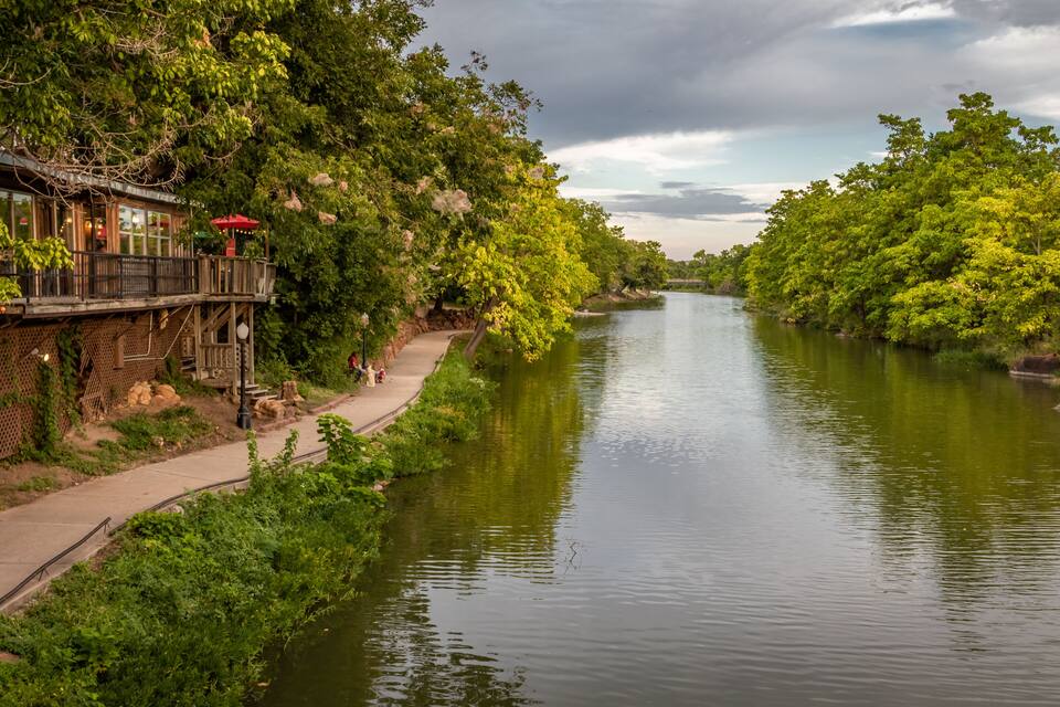 A river with a wooden walkway and a restaurant on the left.