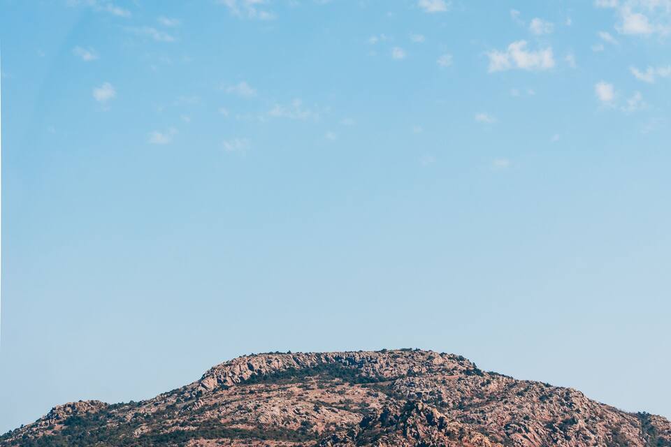 A mountain range with a clear sky and a grassy field in the foreground.