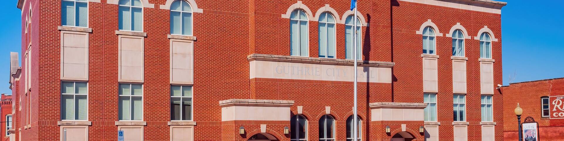 A red brick building with arched windows and a flagpole.