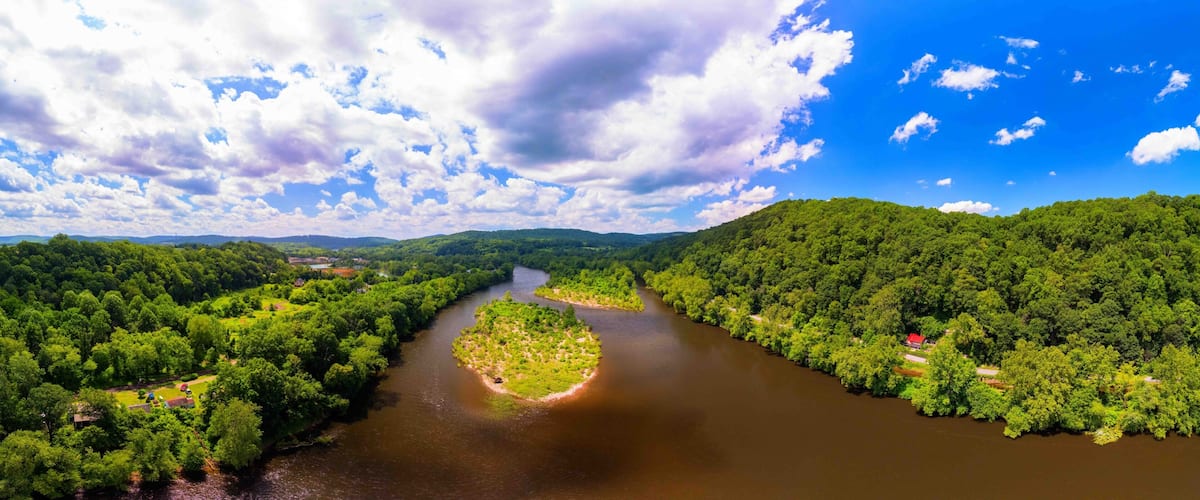 A river winding through a densely forested valley with a clear sky above.