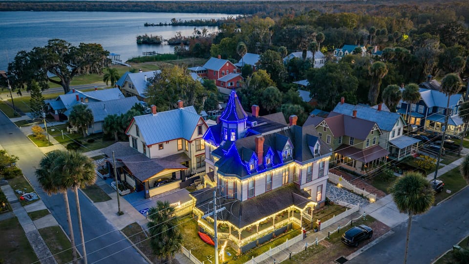 A residential area with a prominent house featuring blue lights and a large porch.