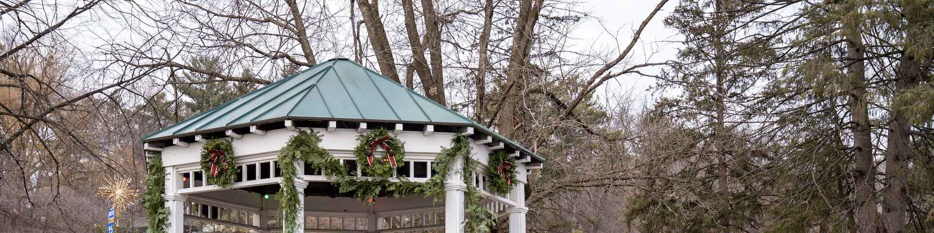 Festive whitewashed gazebo in a park, decorated for Christmas