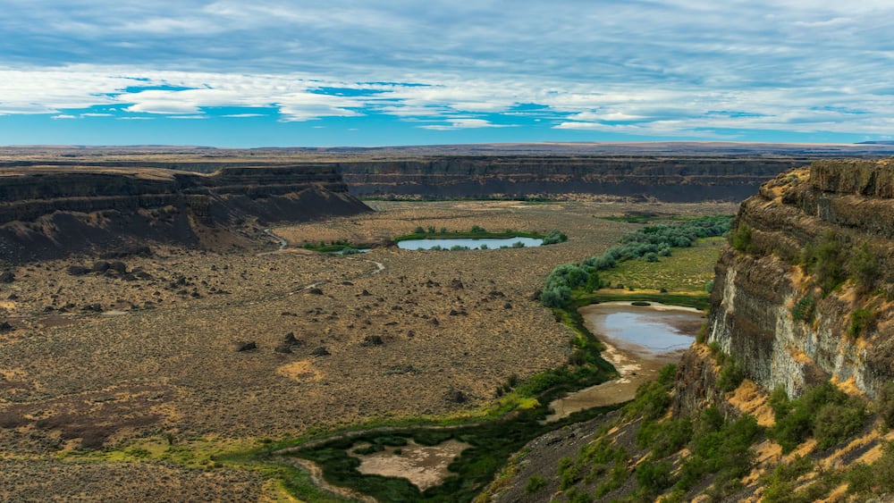 Un vaste canyon traversé par une rivière sinueuse, entouré d’une végétation clairsemée et d’un terrain rocheux.