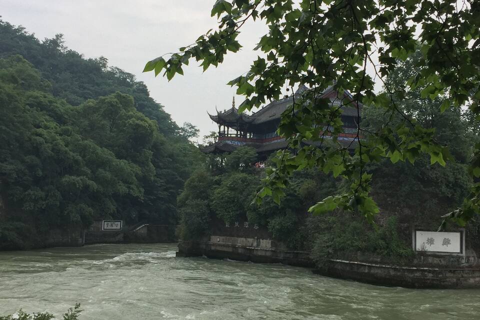 A river with a traditional building on a hillside.