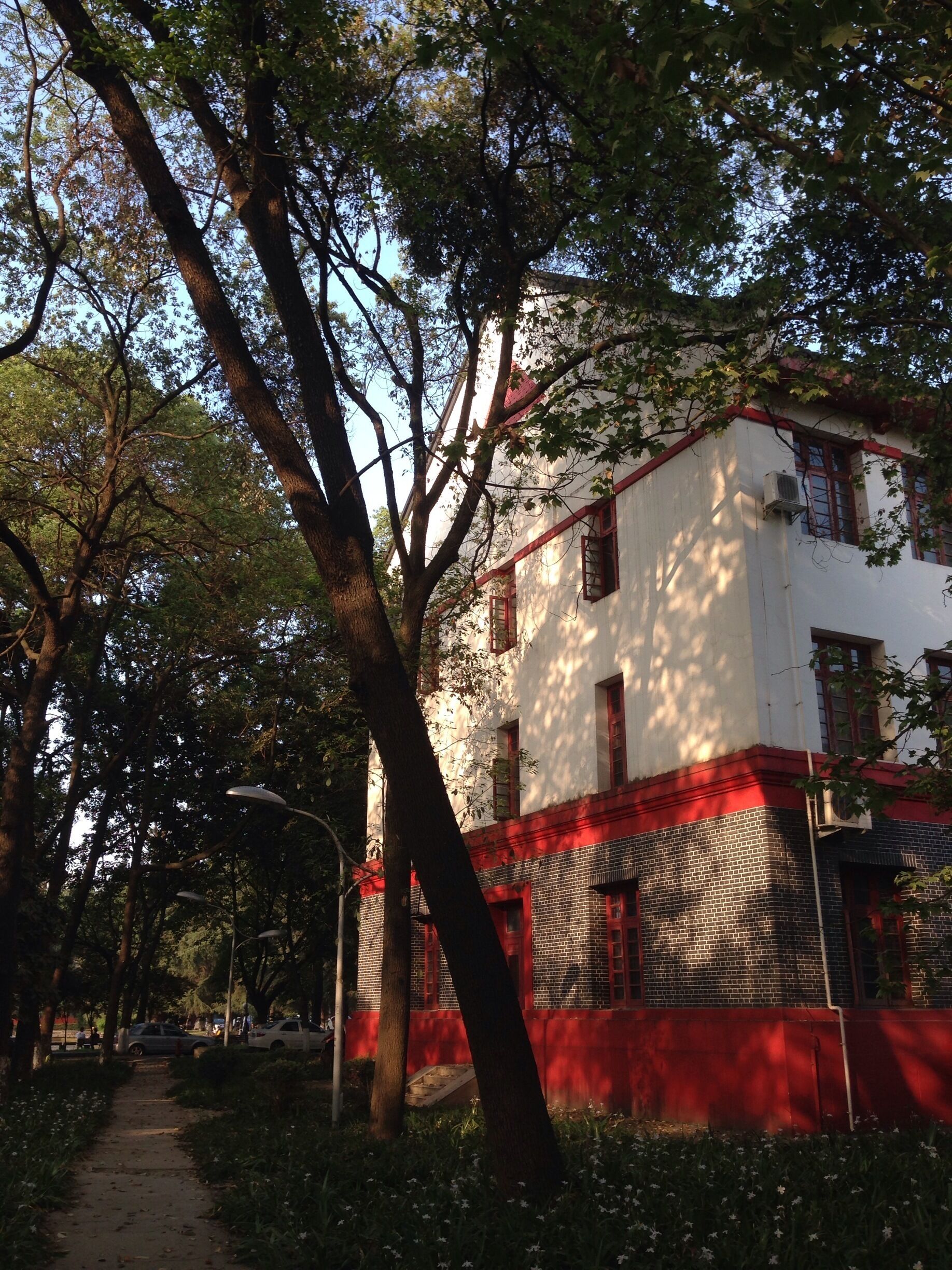 A white building with red accents, surrounded by trees and a pathway.