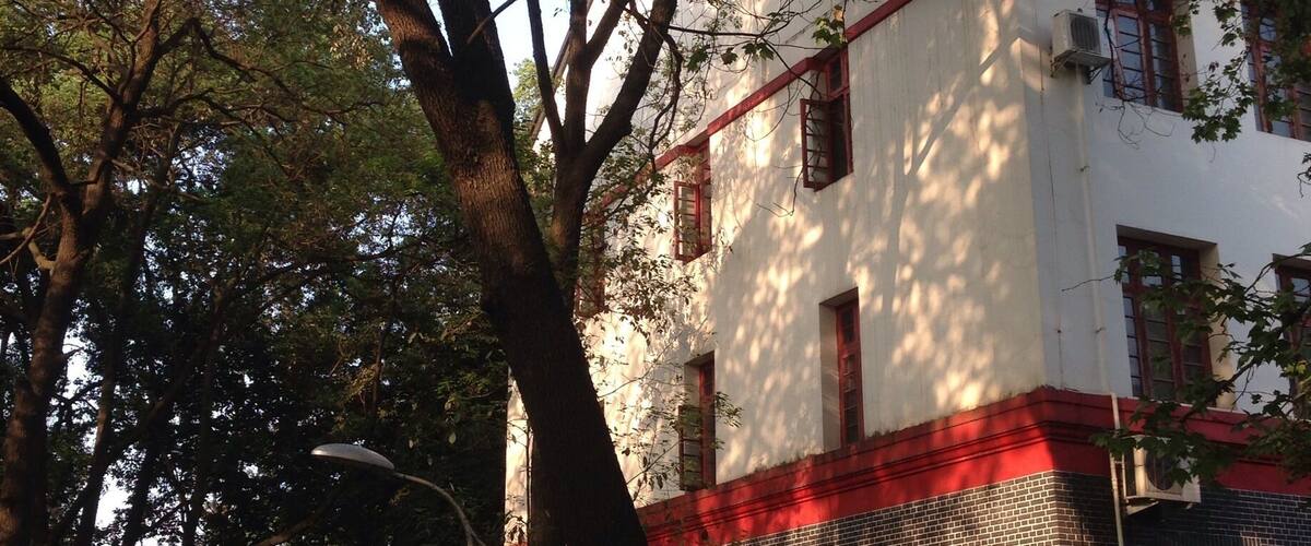 A white building with red accents, surrounded by trees and a pathway.