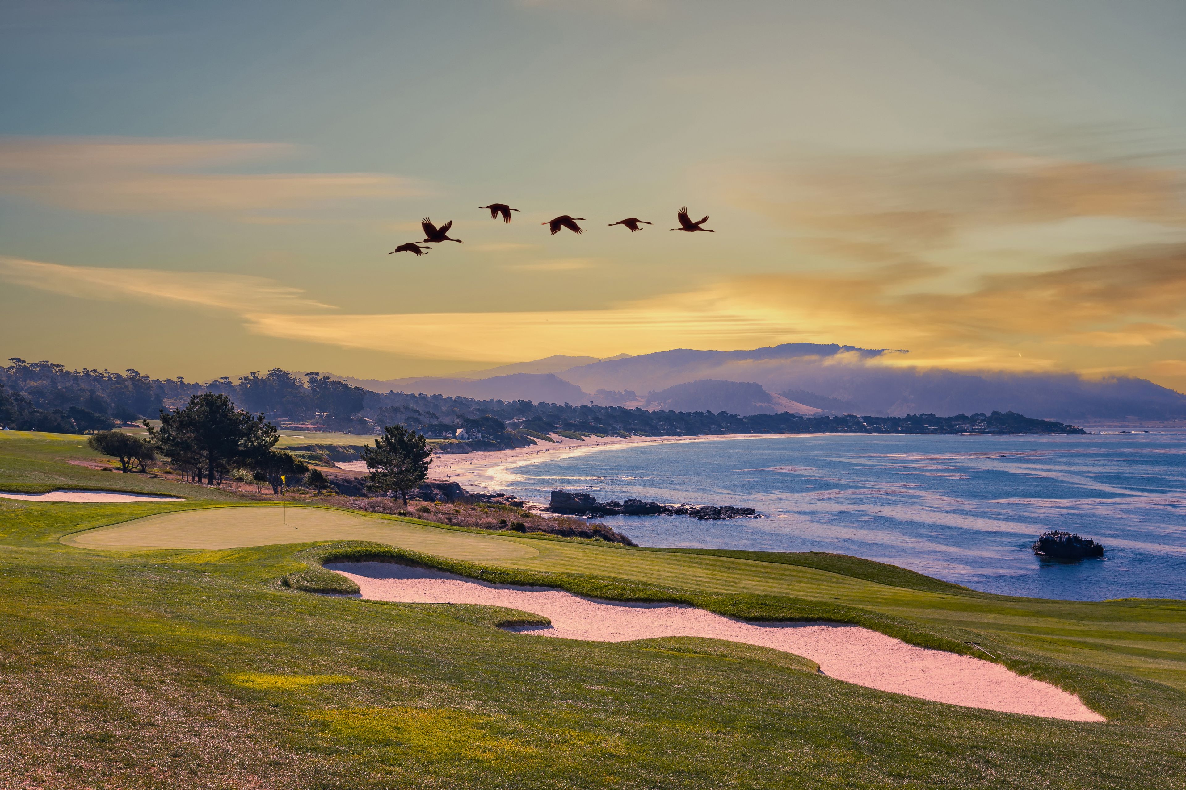 Un campo da golf costiero con bunker di sabbia e vista sull'oceano.
