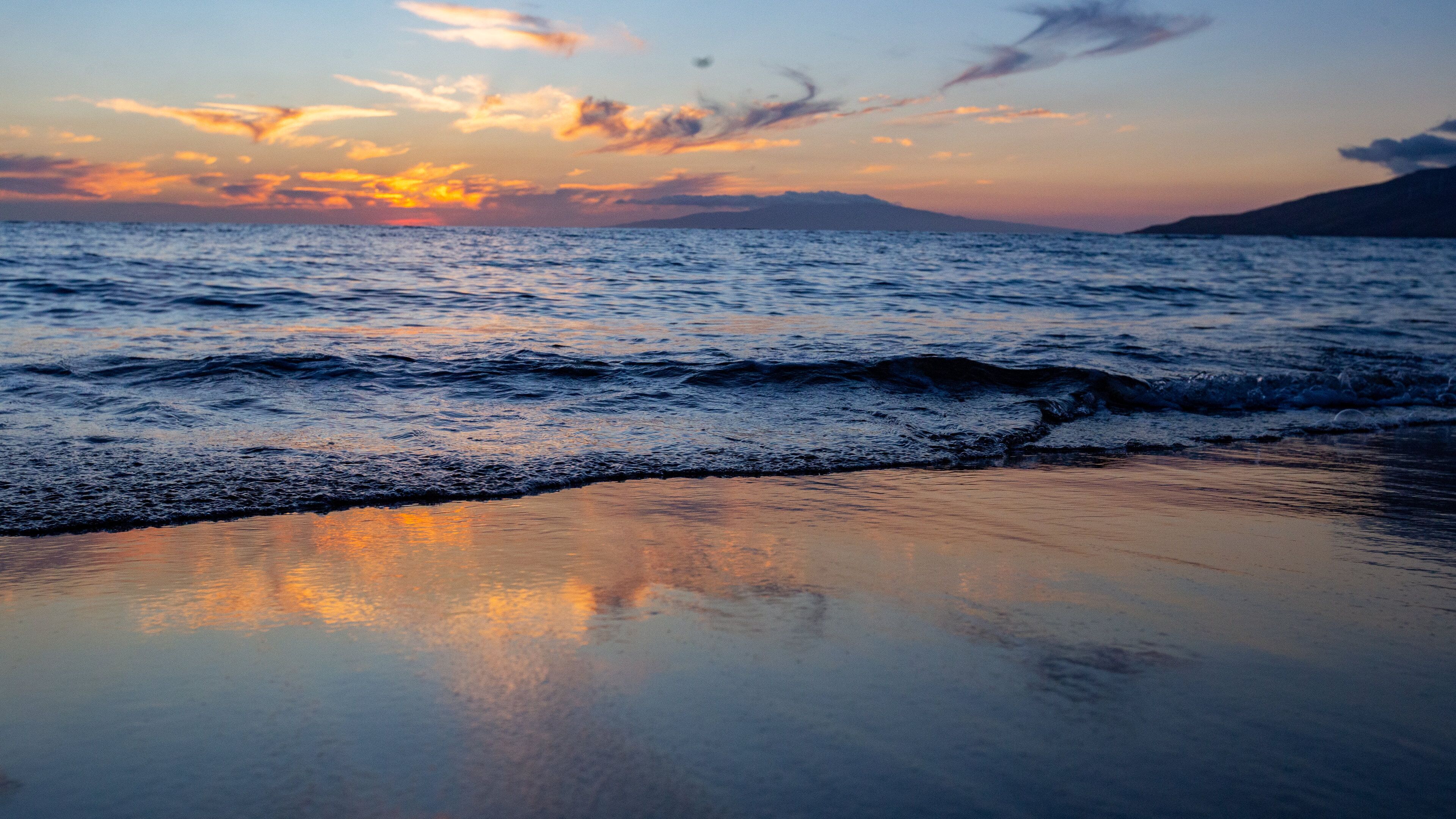 A beach with waves at sunset.