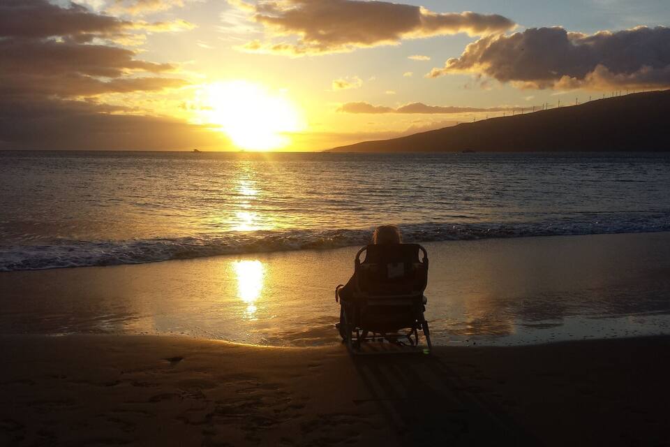 Ein Sonnenuntergang über einem Strand, eine Person im Rollstuhl ist zu sehen.
