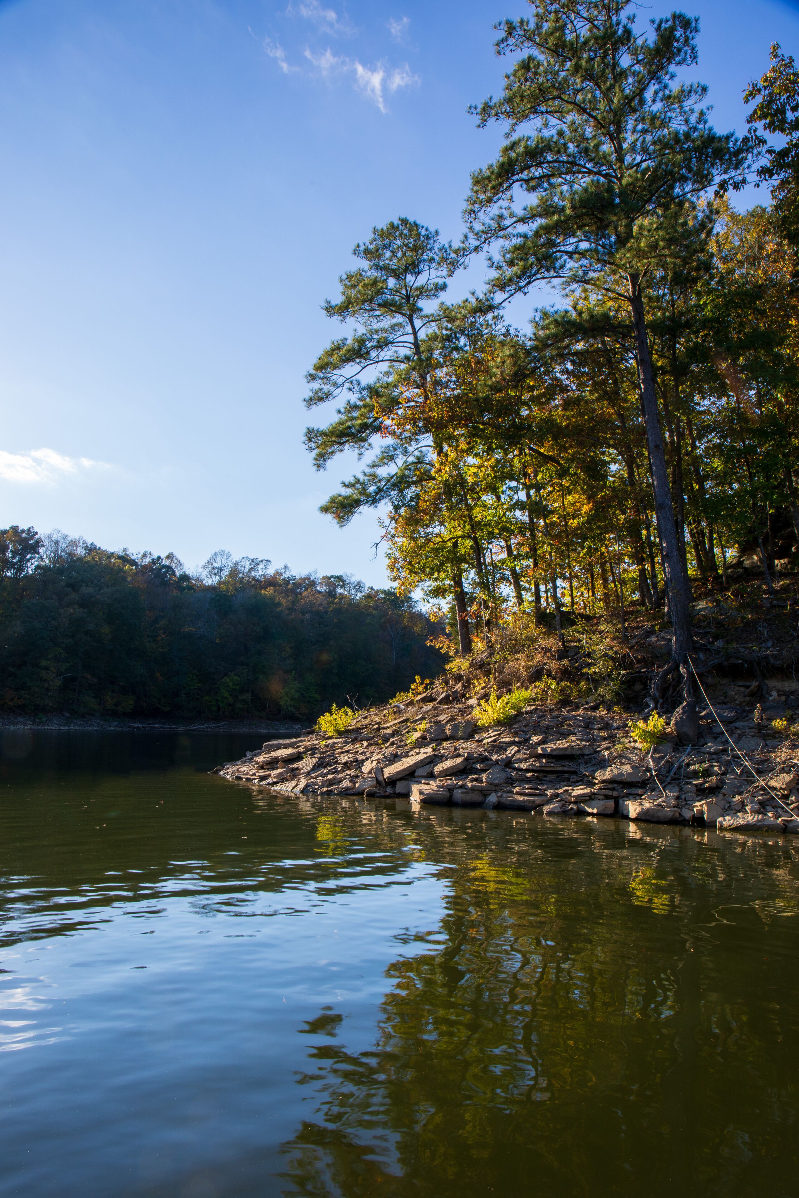 Blue lake background and red leafy tree foreground. Blue water scene.  Blue shoreline on Smith Lake with red leaf branch in the foreground.  Blue  water with colorful leafy foreground.