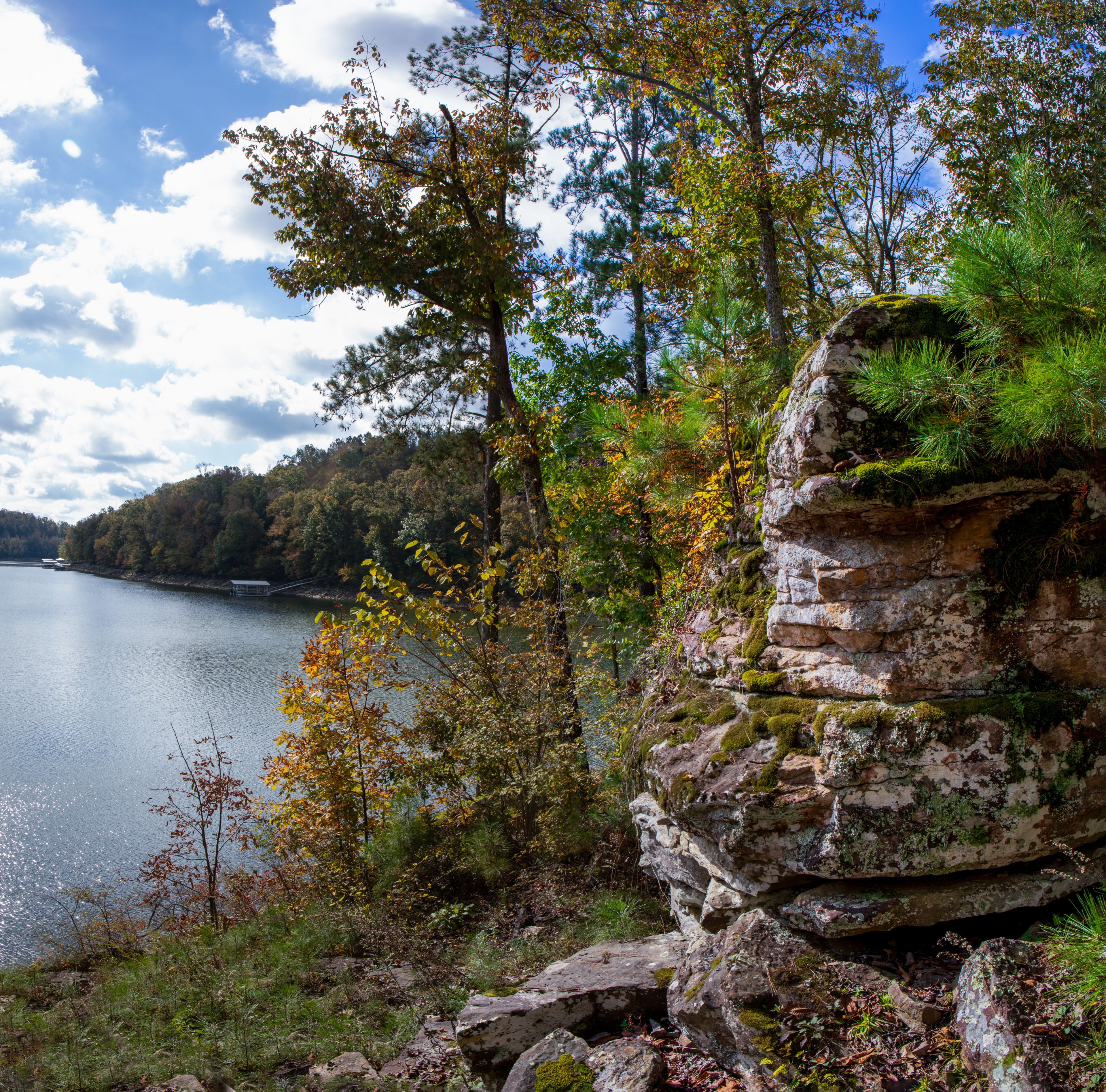 Blue lake background and red leafy tree foreground. Blue water scene.  Blue shoreline on Smith Lake with red leaf branch in the foreground.  Blue  water with colorful leafy foreground.