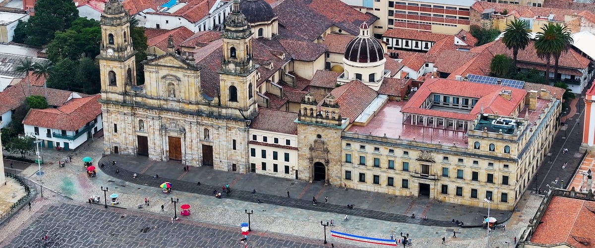 A historic square with a prominent church featuring a bell tower and dome, surrounded by buildings with red-tiled roofs.