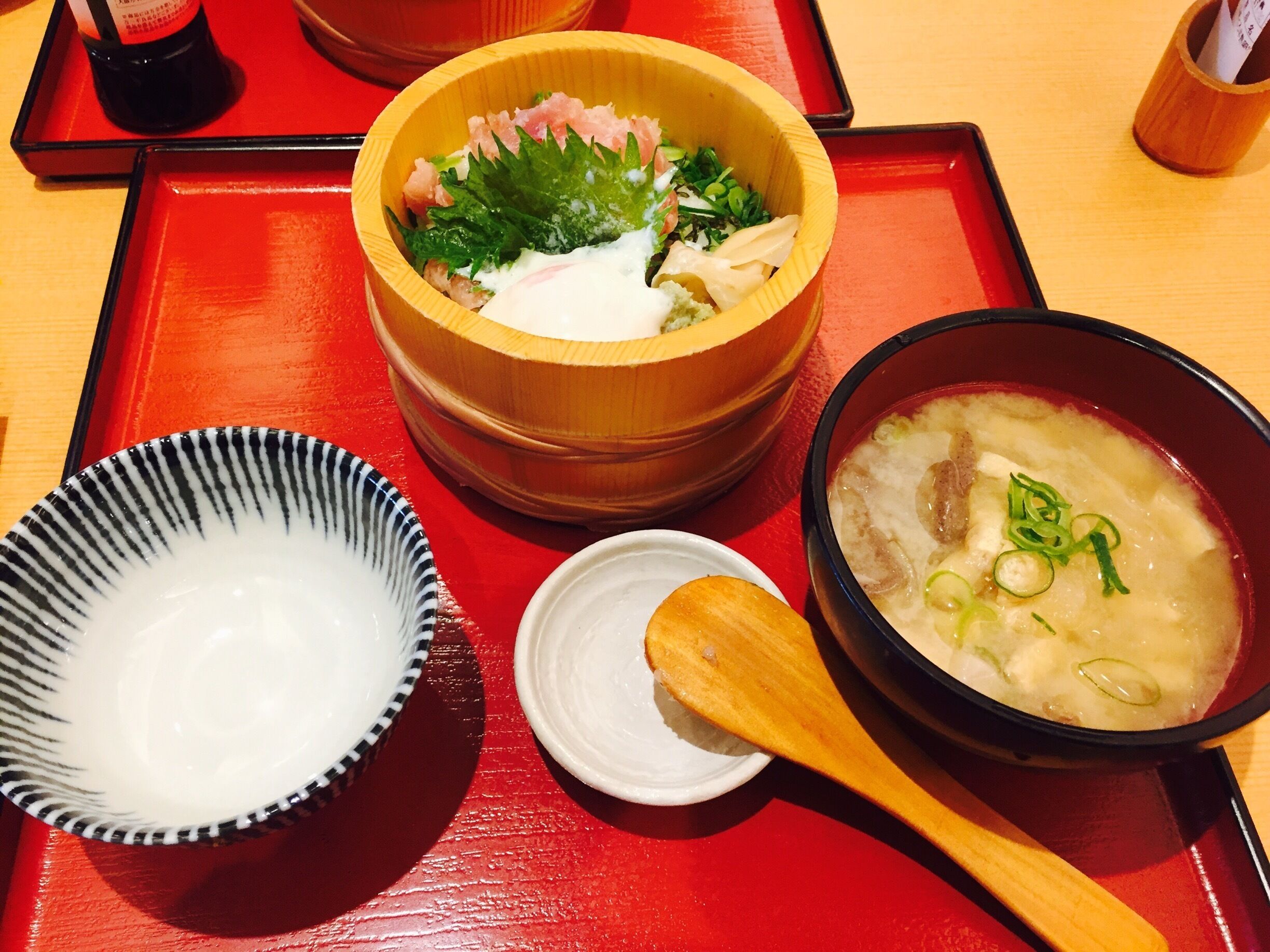 A wooden bowl with a white sauce, a small white dish, and a bowl of soup with green onions.
