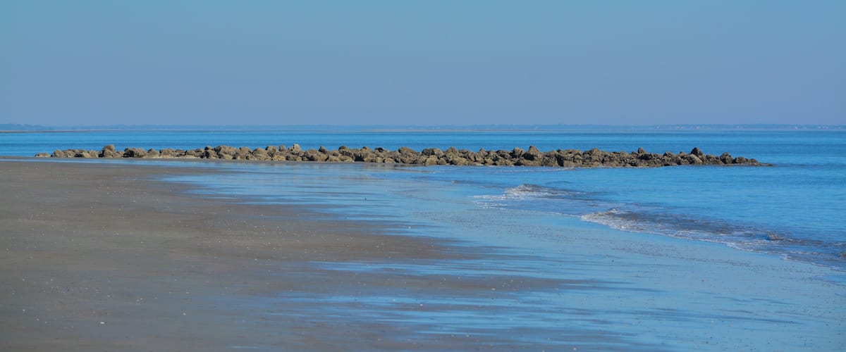 A beach with a rocky breakwater extending into the sea.