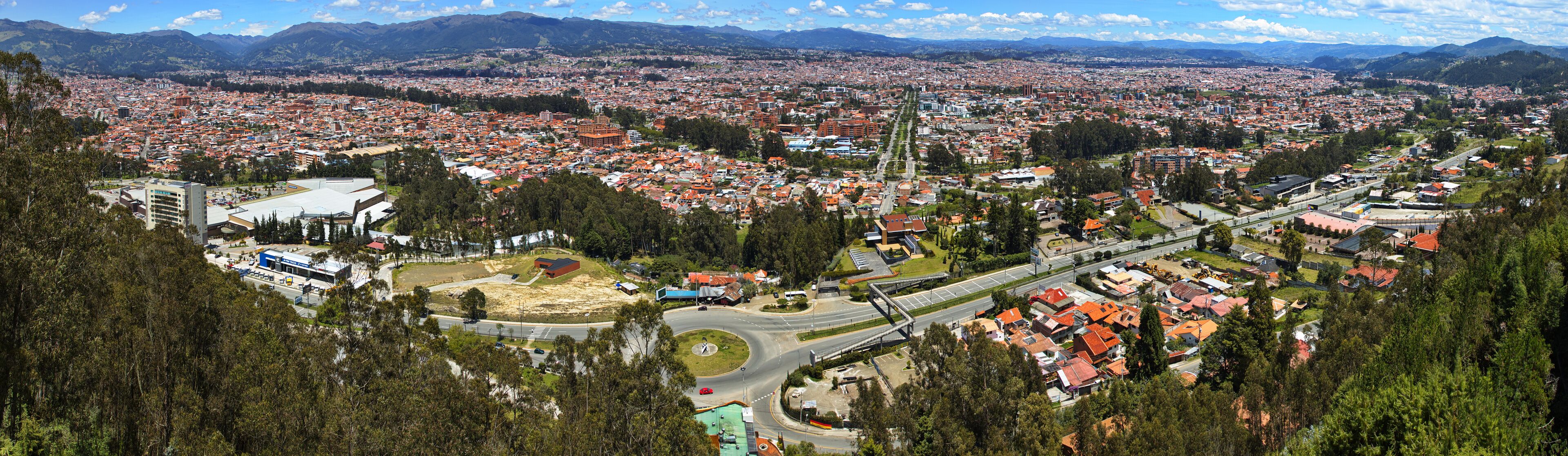 A cityscape with a prominent highway, dense residential areas, and surrounding mountains.