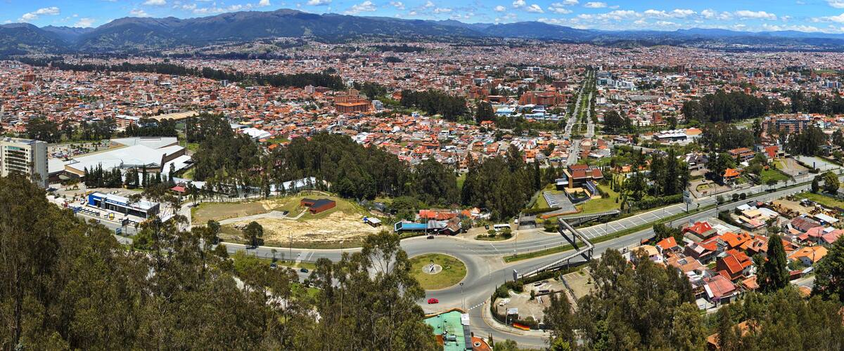 A cityscape with a prominent highway, dense residential areas, and surrounding mountains.