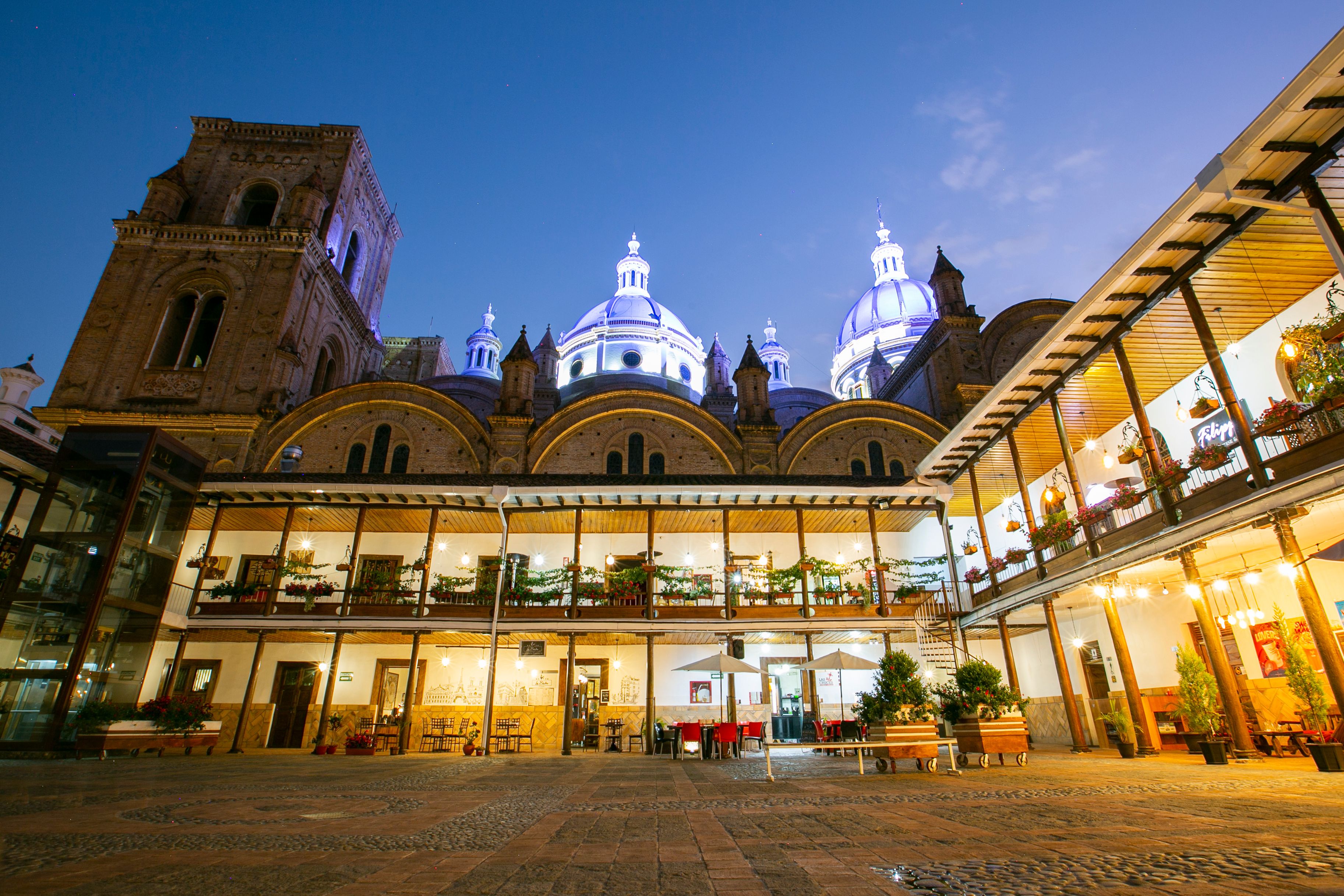 A historic building with domed architecture and a courtyard with outdoor seating.