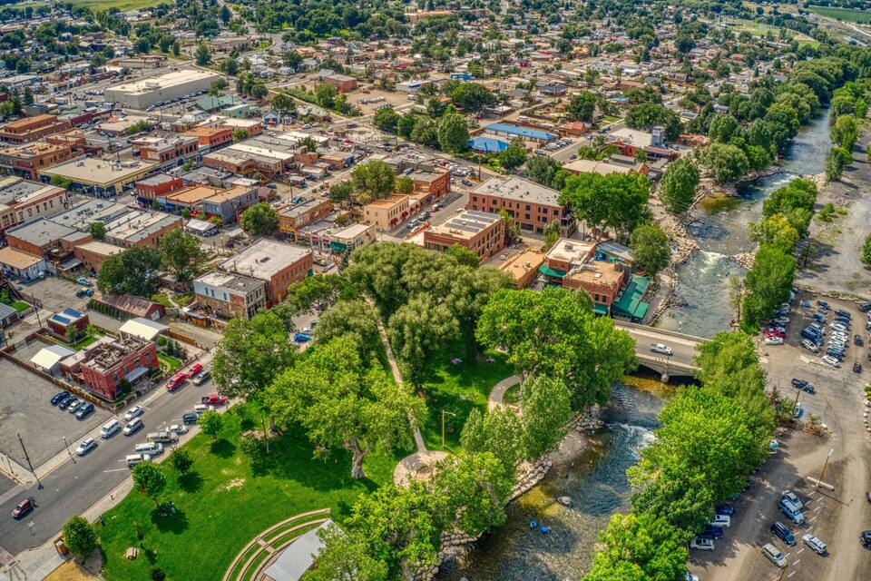 Une vue aérienne d’une ville avec une rivière, des espaces verts et un mélange de bâtiments commerciaux et résidentiels.