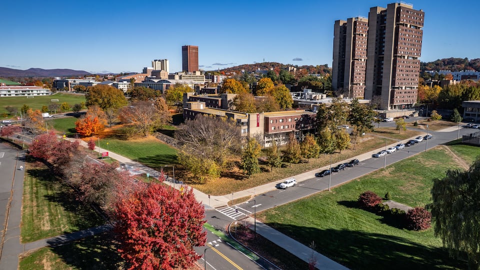 A cityscape with autumn foliage, a prominent red building, and a clear blue sky.