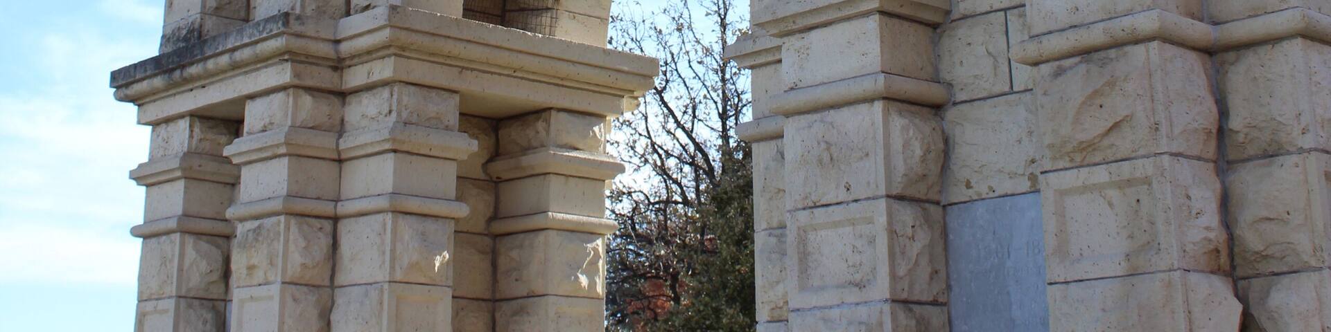 A large stone archway with intricate carvings and a statue on top.