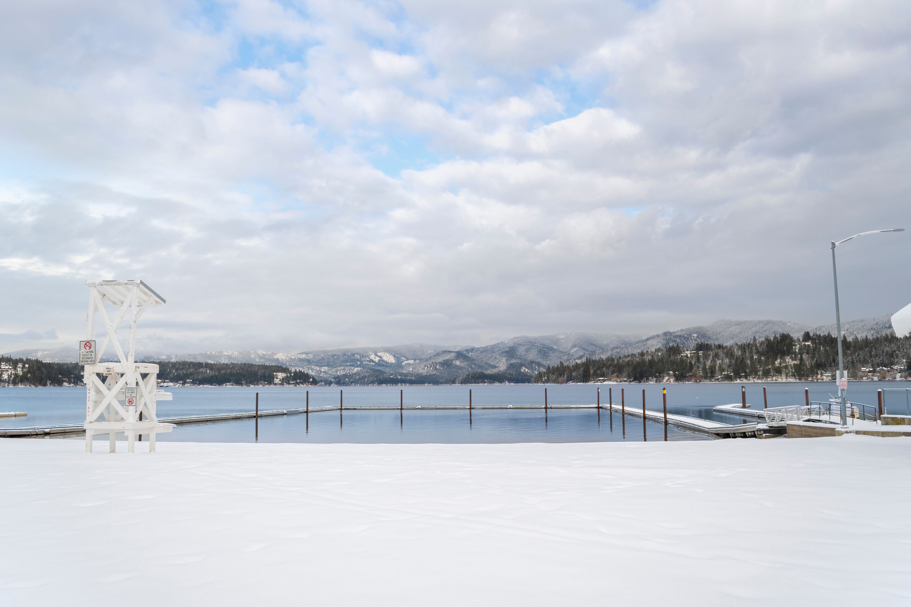Snow covered winter view of the boat dock and swim area of Honeysuckle beach on Hayden Lake, in Hayden Lake, Idaho, USA