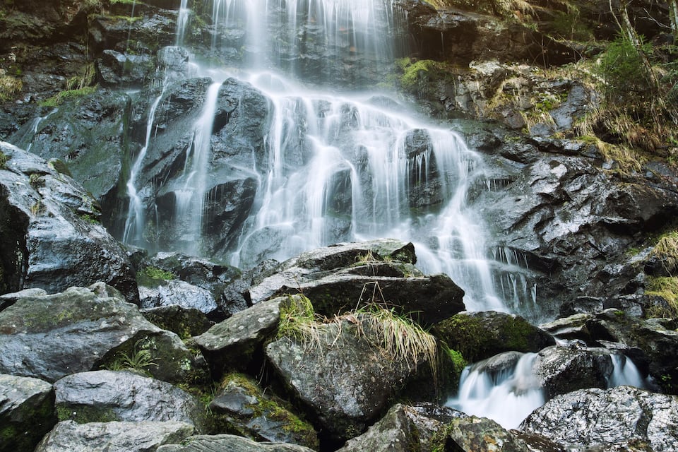 A waterfall cascading over rocks in a forested area.