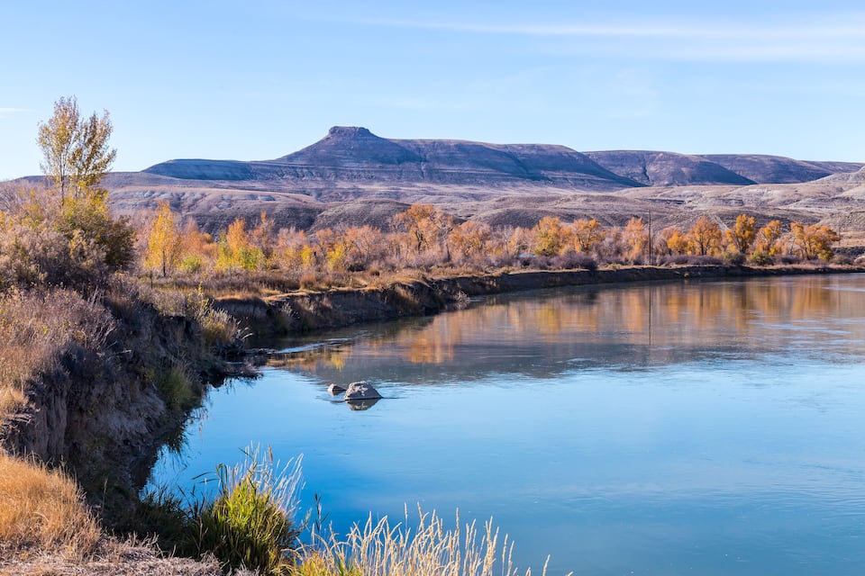 A river with a rocky bank and autumn-colored trees.