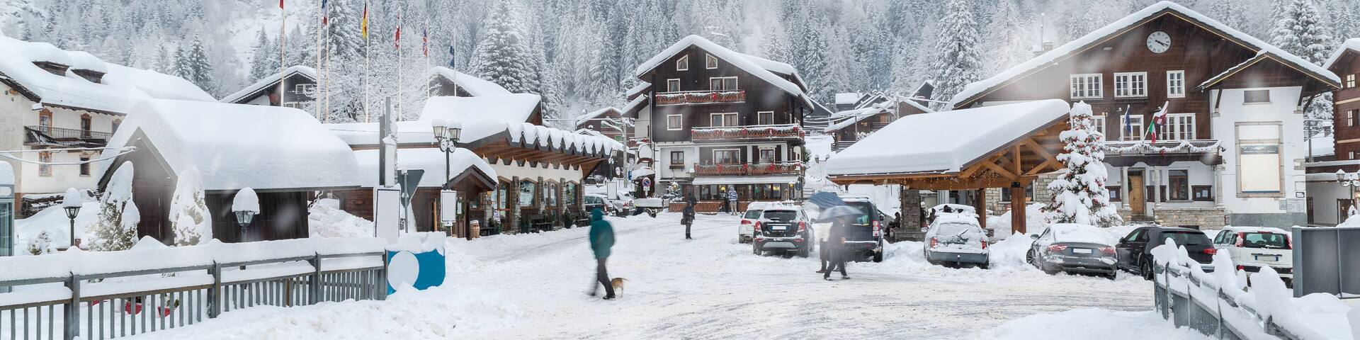 Un village enneigé avec des bâtiments en bois et une route recouverte de neige.