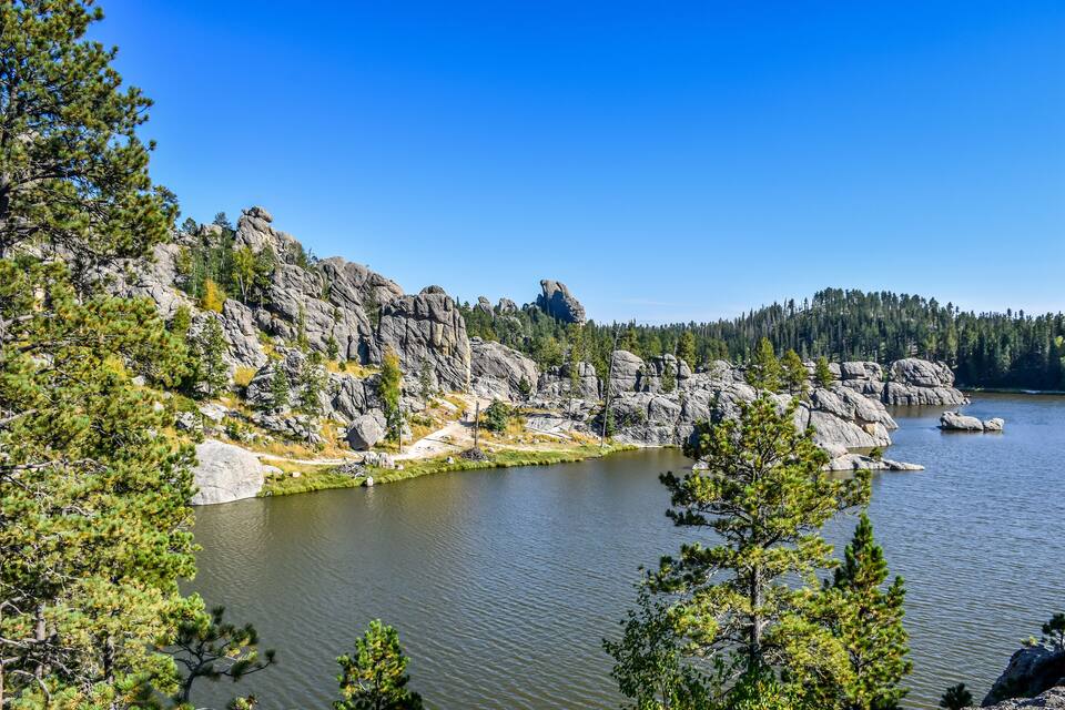 A lake surrounded by rocky terrain and dense forests.