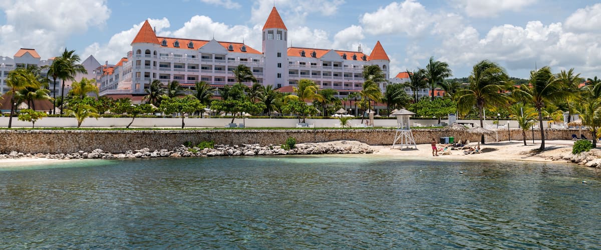A large resort with a tower, palm trees, and a beach.