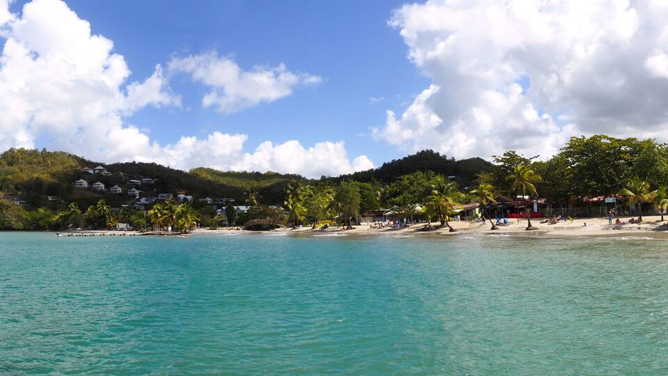 Superb panoramic view from the sea of the beautiful beach of Anse à l'Ane near the village of Trois-Ilets in Martinique facing the city of Fort-de-France