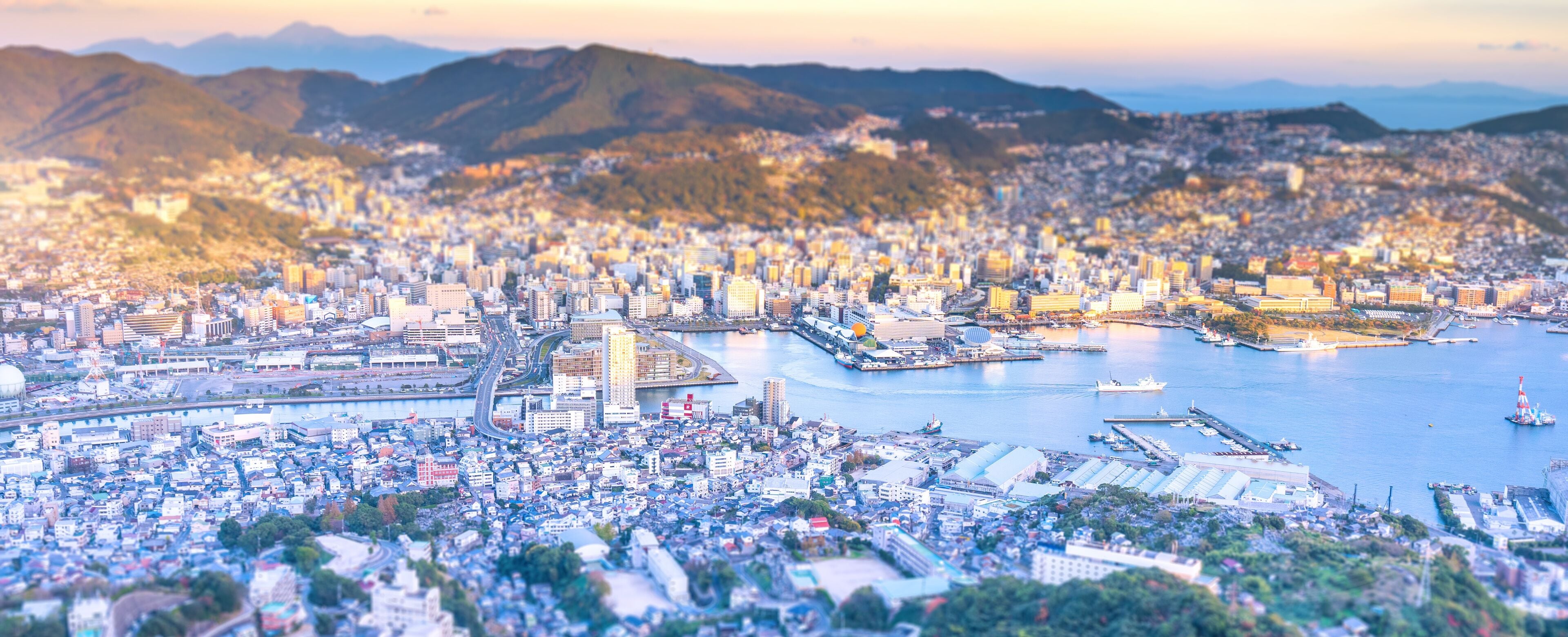 Business concept, tilt shift effect modern cityscape of nagasaki dusk from mount inasa, the new top 3 nightview of the world, aerial view, copy space