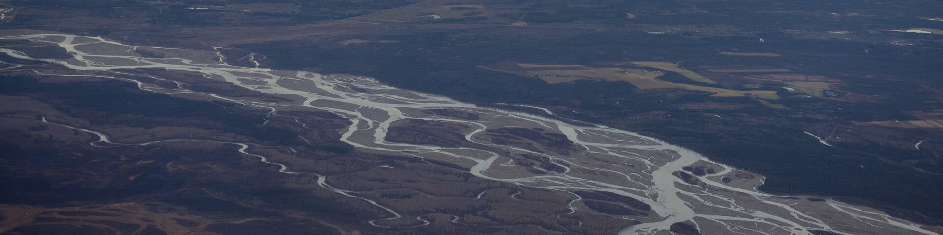 A river winding through a valley with distant clouds.