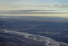 Une rivière serpentant à travers une vallée, avec des nuages qui se dessinent à l’horizon.